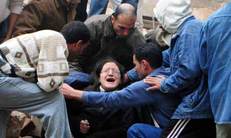 A woman is helped out of the rubble of a collapsed factory building in Alexandria