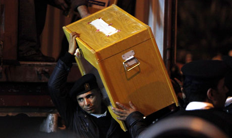 A police officer carries a ballot box to a counting center