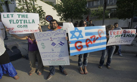 Foreign activists hold placards against the actions taken by the Greek authorities to ban the Gaza F