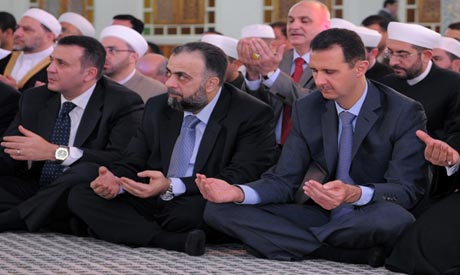 Syrian President Bashar Assad, right, prays during the Eid al-Fitr prayer at Hafez al-Assad mosque, 