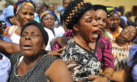 Women weep over their loved ones who died in the Christmas day bomb explosion at St. Theresa