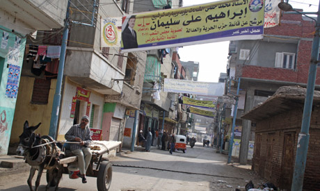 A farmer drives a makeshift carriage, passing under one of the numerous banners of FJP candidate Ibr