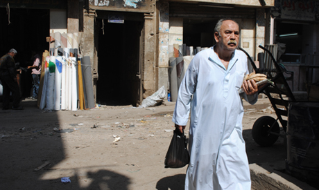 Old man holding bread, newspaper and grocery bag. Lower-class Cairo district. (Photo: Sarah El-Rashi