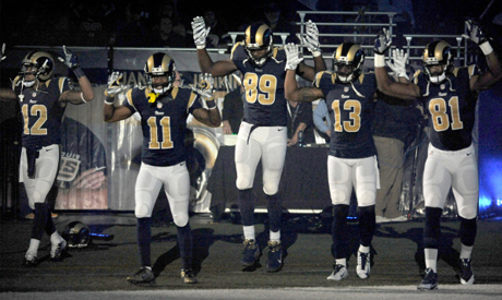 St. Louis Rams players raise their arms in awareness of the events in Ferguson