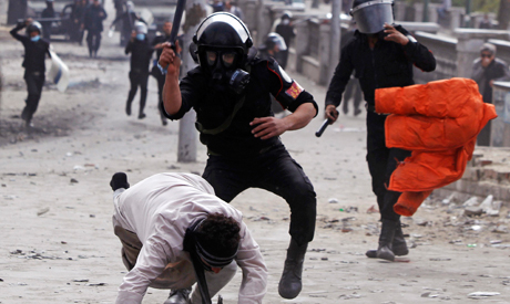 Riot policemen beat a protester opposing ousted Egyptian President Mohamed Morsi 