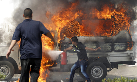 Plain clothes policemen try to extinguish a police car