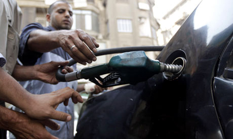 a worker fills the tank of a car at a petrol station