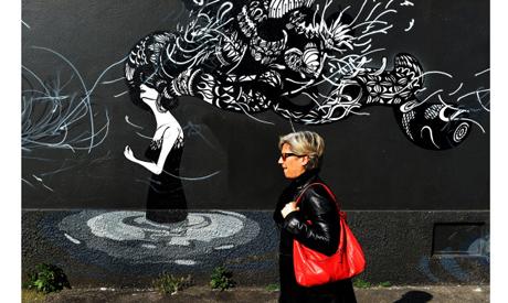This photo taken on April 2, 2014 shows a woman walking by a mural by Brazilian artist Herbert Bagli
