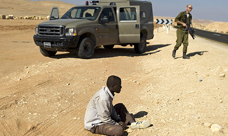 An African man sits on the ground after being detained by Israel