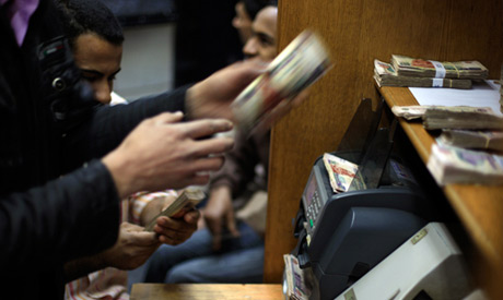 Egyptians count money at a currency exchange office
