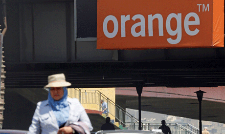 People walk past a sign of French telecom operator Orange in Cairo (Reuters)