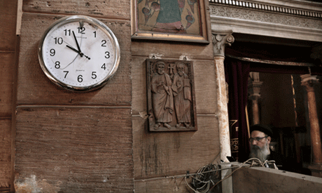 A damaged clock and Coptic clergyman at the scene inside the St. Mark Cathedral in central Cairo, fo