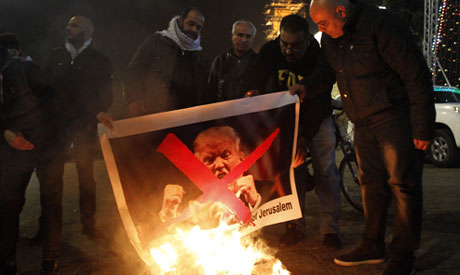 Palestinian protesters burn pictures of US President Donald Trump at the manger square in Bethlehem 