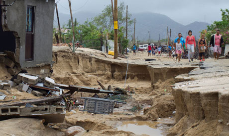 Residents walk along a damaged street in the aftermath of Tropical Storm Lidia in Los Cabos