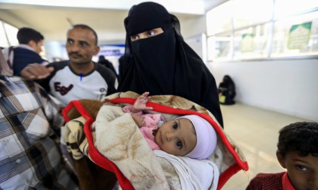 Yemeni woman carries an ill child