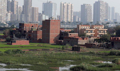 A view of houses and farmland on an island on the River Nile in front of high-rise buildings in Cair