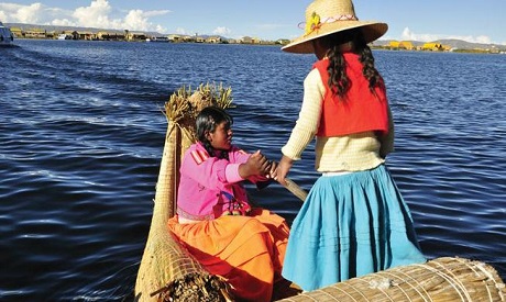 Two young women row in Lake Titicaca, the highest commercially navigable body of water in the world,