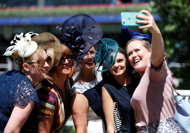  Racegoers take a selfie before the start of the racing (Reuters)