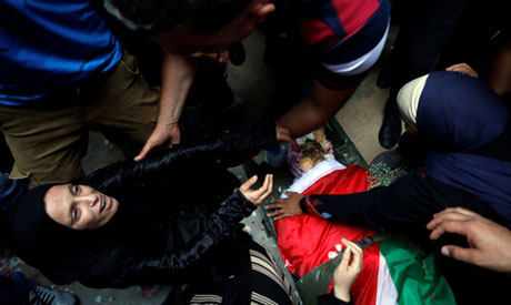  A relative of Palestinian Ezz El-Deen al-Tamimi mourns as she looks at his body during his funeral 