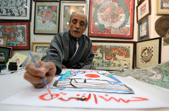 Artist, Hassan el-Shark, paints a piece of art with his own handcrafted colours, at his gallery in M