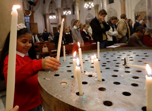 A girl lights candle during a mass on Christmas eve at Saint Joseph