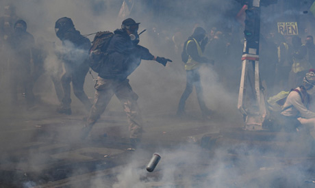Protesters stand in tear gas smoke prior to the start of the annual May Day rally in Paris on May 1,