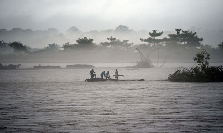 Indian men catch a tree in the flooded Manas river, following heavy rainfall in Baksa district of As
