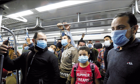 People wearing protective face masks stand inside Cairo