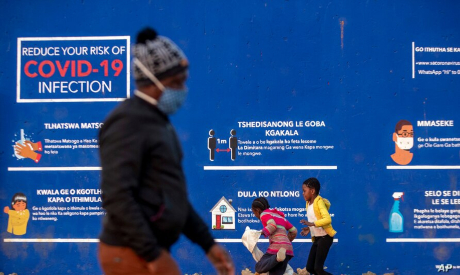 People walk past a COVID-19 advertisement in South Africa