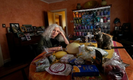 American woman poses with her cat, with food she recently obtained from a local food bank