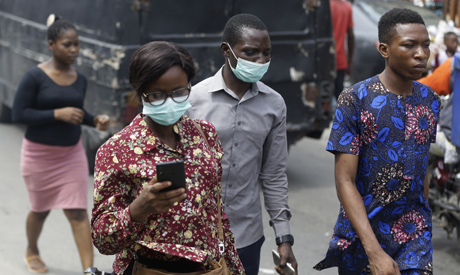 People wearing face mask walk through a busy Market in Lagos, Nigeria, (AP)
