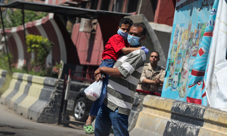 A man wearing a face mask carries his son on the street, as the outbreak of the coronavirus disease 