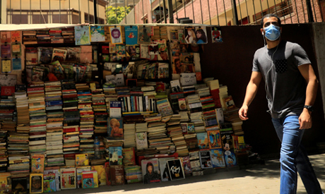 A man wearing a protective face mask walks past a bookstand on street in central Cairo, amid concern