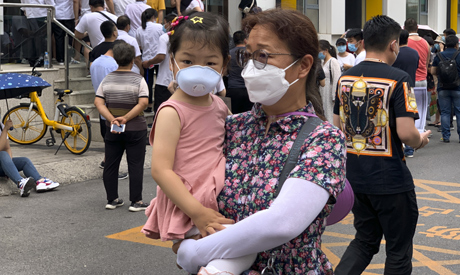 A woman and a child wearing protective face masks to help curb the spread of the new coronavirus wal