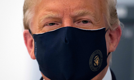 US President Donald Trump wears a mask as he tours a lab where they are making components for a pote