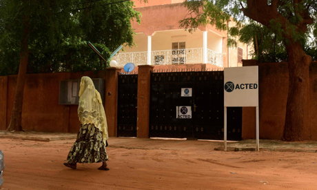 A woman walks past the gates of the local office of the French aid group ACTED in Niamey on August 1