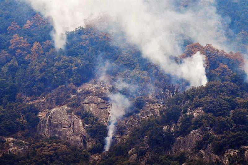 Smoke rises from a mountainside adjacent to Moro Rock during a tour of the KNP Complex fire burn are