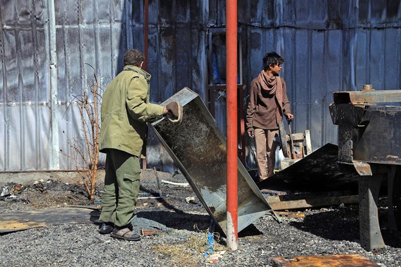Yemenis inspect a damaged factory