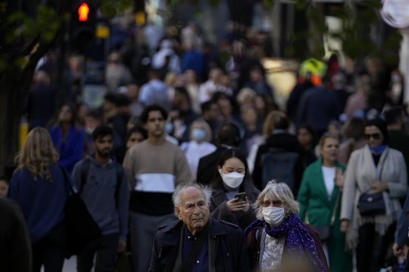 FILE - People wearing face masks walk along the Oxford Street shopping area of central London, Oct. 