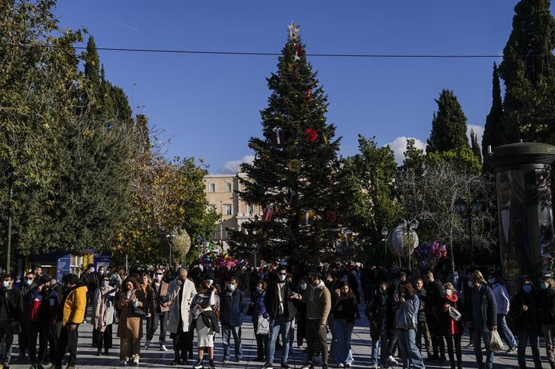 people stand in front of Christmas tree