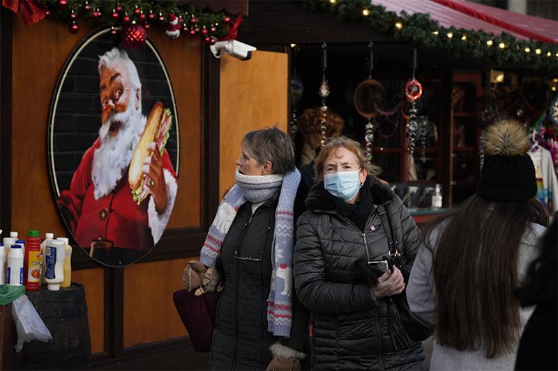 eople walk past an image of Santa on the side of a stall in a Christmas market, in Trafalgar Square,