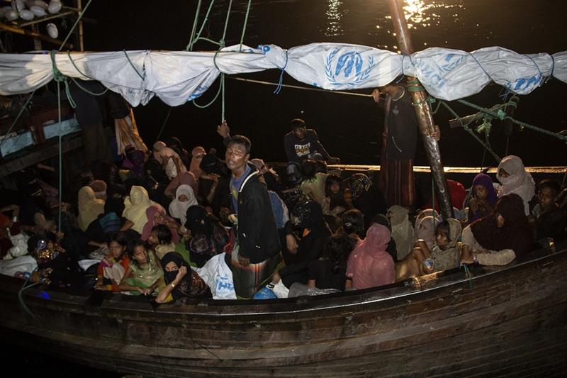 Rohingya refugees sit in a wooden boat