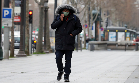 A man wearing a protective face mask walks in Paris