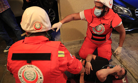 Civil defense workers give oxygen to a man who fainted from the tear gas during a riot between prote