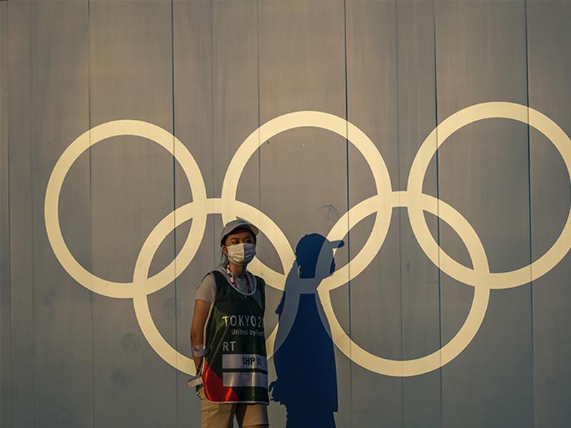 A volunteer walks past the Olympic rings ahead of the 2020 Summer Olympics, on Thursday, July 22, 20