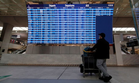 A passenger looks at a departures board at Paris Charles de Gaulle airport