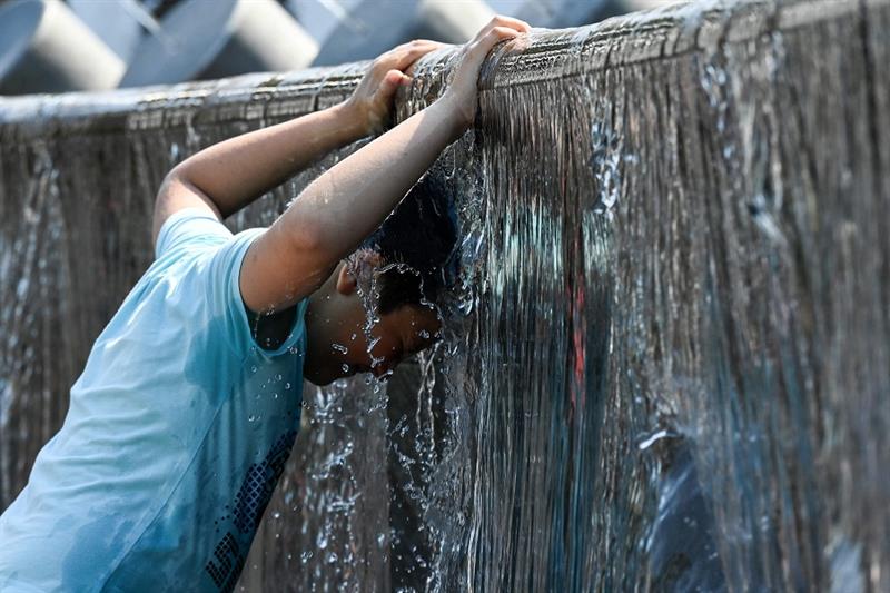 A boy cools off in a fountain during a hot summer day in downtown Moscow