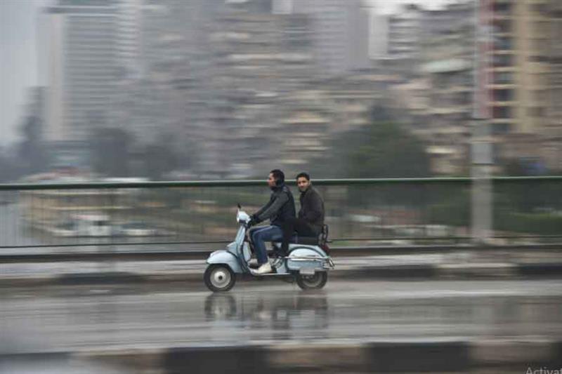 Egyptian men ride a scooter in the rain on December . AFP
