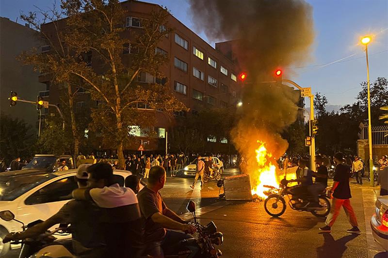 File photo: police motorcycle and a trash bin are burning during a protest over the death of Mahsa A