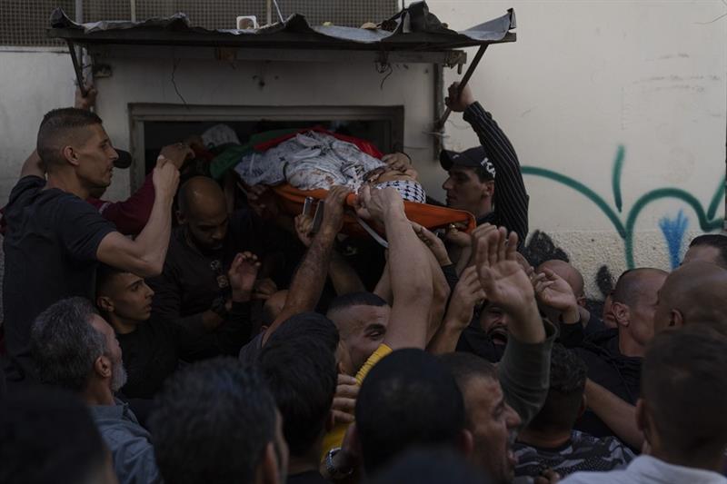 Mourners carry the body of Ramzi Zabarah, 35, out of the family house during his funeral in the West